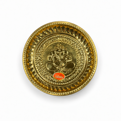 A 9-inch brass puja plate featuring an embossed motif of Lord Ganesha at the center and a decorated rim, centered on a solid white background. Available in the UK at theindianshelf.co.uk.