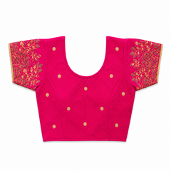 A bright magenta pink short-sleeved stretchable readymade saree blouse with hand-embroidered golden leaf patterns on the sleeves and small gold floral motifs across the front, laid flat against a solid white background. Available in the UK at theindianshelf.co.uk.