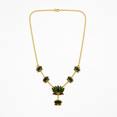 A delicate gold-plated chain necklace featuring multiple emerald-green enamel lotus motifs arranged along the bottom, centered on a solid white background. Available in the UK at theindianshelf.co.uk.