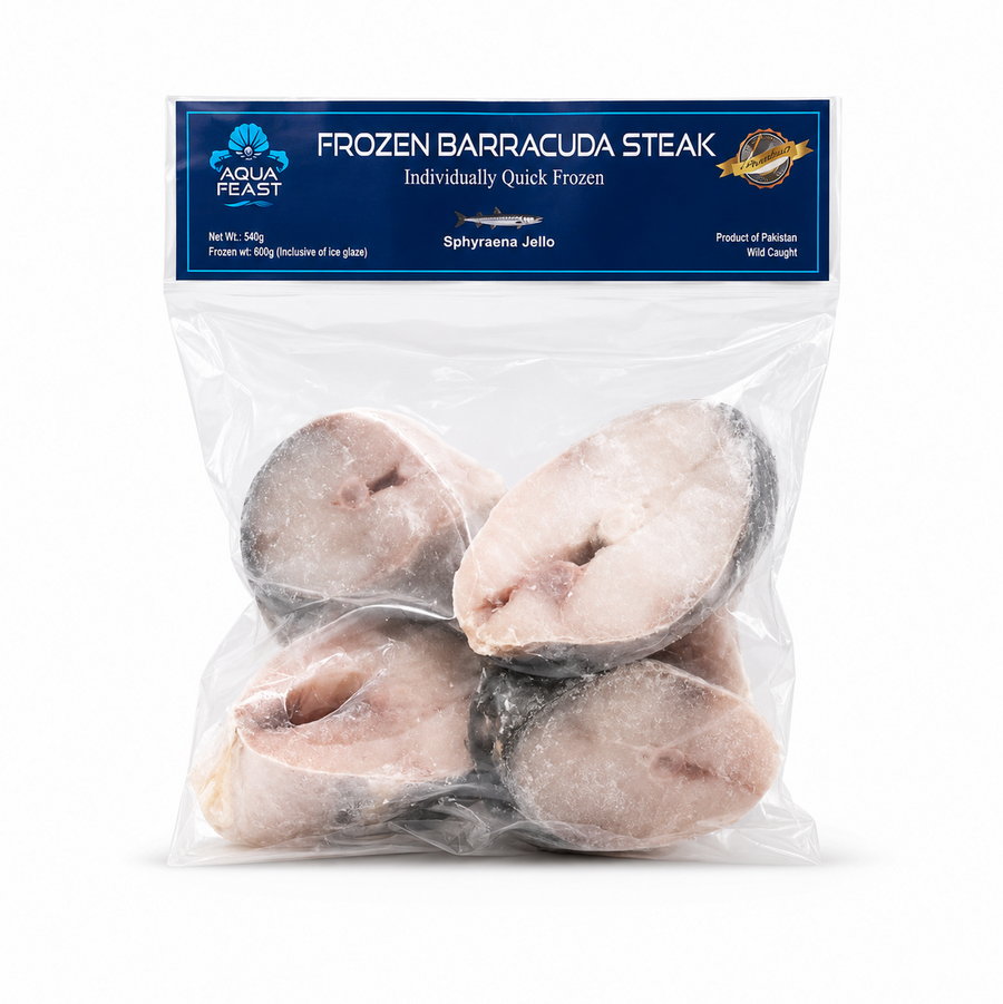 A professional studio product shot of a clear, stand-up freezer pouch containing Aqua Feast Frozen Barracuda Steaks against a solid white background. The top of the bag features a prominent dark blue horizontal header displaying the light blue "AQUA FEAST" shell logo, bold white text reading "FROZEN BARRACUDA STEAK", and product details including "Net Wt.: 540g" and "Wild Caught". This product is available in the UK at theindianshelf.co.uk.