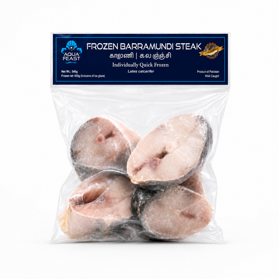 A studio product shot of a clear plastic bag containing four frozen Barramundi fish steaks against a solid white background. The top of the resealable packet features a dark blue header label branded with the "AQUA FEAST" logo, the text "FROZEN BARRAMUNDI STEAK", and product weight specifications. Available in the UK at theindianshelf.co.uk.
