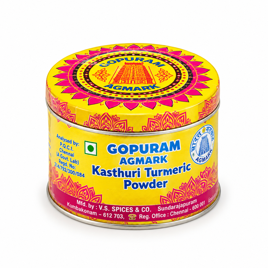 A decorative round tin of Gopuram Agmark Kasthuri Turmeric Powder with vibrant yellow and pink patterns, centered on a solid white background. Available in the UK at theindianshelf.co.uk.