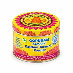 A decorative round tin of Gopuram Agmark Kasthuri Turmeric Powder with vibrant yellow and pink patterns, centered on a solid white background. Available in the UK at theindianshelf.co.uk.