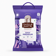 A professional studio product shot of a purple woven fabric bag of India Gate Daily Premium Basmati Rice featuring a top rope carrying handle against a solid white background. The front displays a central white shield block housing the brown historic India Gate monument illustration above the bold white brand text "INDIA GATE" on a dark brown banner. Below this, the title reads "DAILY PREMIUM" in dark purple lettering.This product is available in the UK at theindianshelf.co.uk.