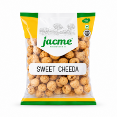 A studio product shot of a clear pillow pouch filled with small, golden-brown Jacme Sweet Cheeda snack balls isolated against a white background. The clean packaging features a white, yellow, and green header label with a rustic village illustration above the prominent product title.