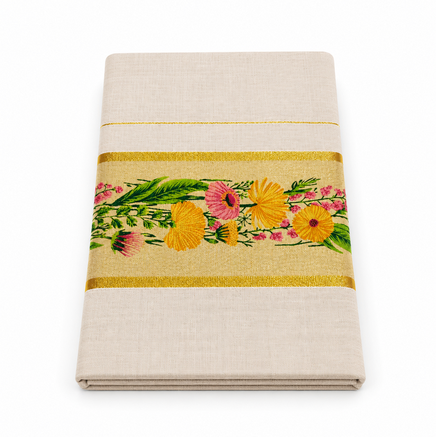 A studio product shot of a neatly folded Kerala Floral Set Saree on a plain white background. The off-white fabric displays a broad golden border intricately embroidered with vivid yellow and pink flowers with green leaves. Available in the UK at theindianshelf.co.uk.