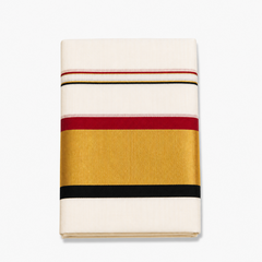 A neatly folded off-white Kerala cotton double set mundu displayed on a solid white background, featuring a wide metallic gold zari band framed by maroon and black border stripes. Available in the UK at theindianshelf.co.uk.