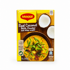 A professional studio product shot of a 300g cardboard box of Maggi Real Coconut Milk Powder isolated against a pure white background in image_7c67ac.jpg. The bright yellow packaging features the red Maggi brand logo, illustrations of halved fresh coconuts, and a bowl of delicious, creamy vegetable curry made with coconut milk. This product is available in the UK at theindianshelf.co.uk.