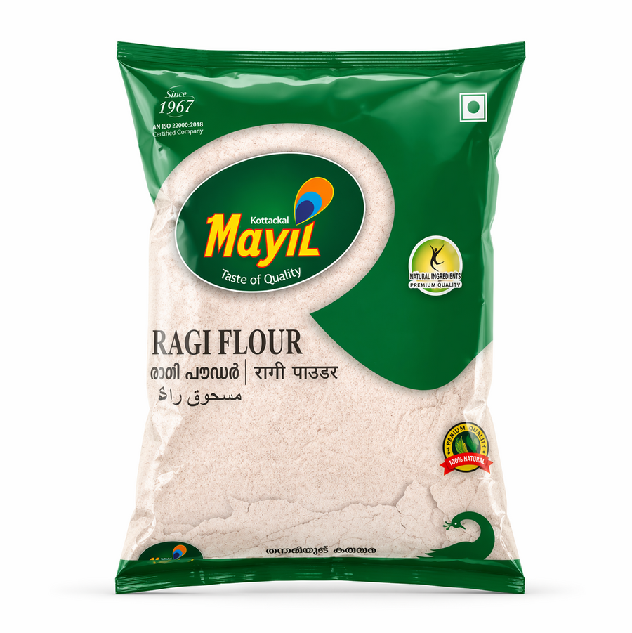 A high-quality studio shot of a packet of Mayil Ragi Flour. The packaging features a vibrant dark green design with a large green oval containing the "Mayil" peacock logo and the slogan "Taste of Quality". The words "RAGI FLOUR" are prominently displayed in bold black text, with the name also provided in Malayalam, Hindi, and Arabic. The packet includes several quality seals, such as "Natural Ingredients Premium Quality" and "100% Natural"This product is available in the UK at theindianshelf.co.uk.