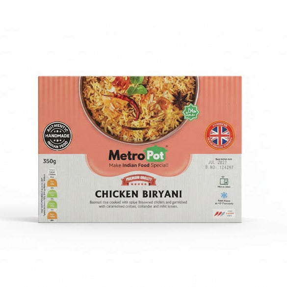 A white and peach-colored box of Metro Pot Chicken Biryani (350g). The packaging features a top-down view of aromatic Basmati rice cooked with spiced chicken, garnished with caramelized onions, coriander, and mint leaves. The label describes it as "Authentic Handmade Indian Food" and prominently displays the "Produced in the UK" logo along with a Halal certification seal.This ready-to-eat meal is available for purchase in the UK at theindianshelf.co.uk.