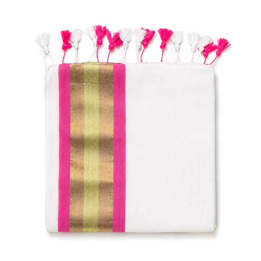 A neatly folded off-white mulcotton saree centered on a solid white background, featuring a tri-color vertical border with magenta pink, golden kasavu, and teal green stripes, finished with bright red handcrafted tassels along the bottom fringe. Available in the UK at theindianshelf.co.uk.