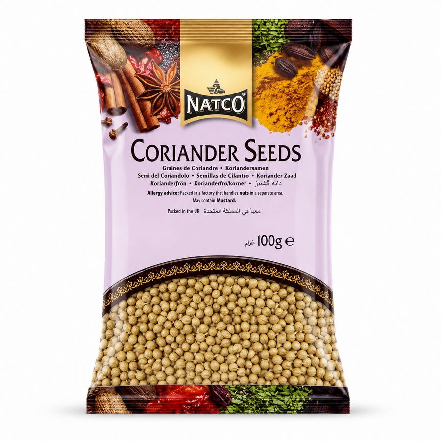 A studio product shot of a 100g vertical pillow pouch of Natco Coriander Seeds against a white background. The top of the pouch displays an artistic border containing images of star anise, cinnamon, nutmeg, and turmeric powder. The black and gold "NATCO" is centered directly above the prominent title "CORIANDER SEEDS". The lower half features a large, transparent crescent window that clearly displays the round, golden-brown whole coriander seeds inside.