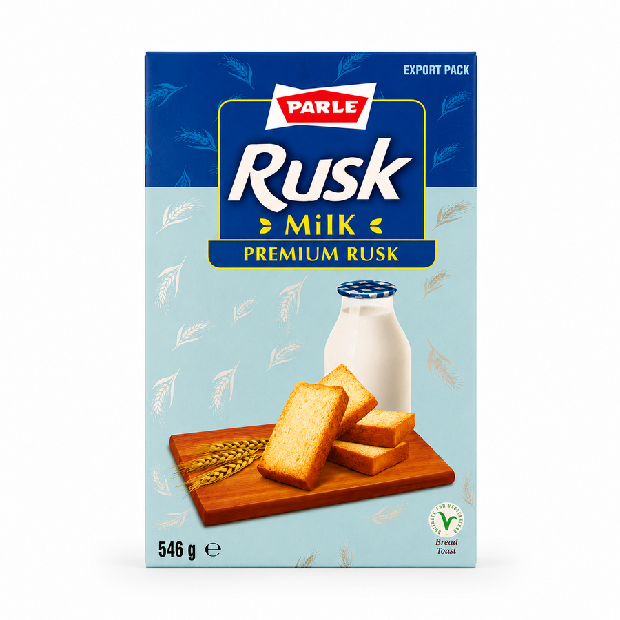 A professional studio product shot of a 546g export cardboard box of Parle Premium Milk Rusk isolated against a pure white background in image_97aa6f.jpg. The packaging features a two-tone blue design with the red and white Parle logo above the prominent product title "Rusk Milk". The lower section displays a wooden cutting board holding crispy golden rusks next to ears of wheat and a fresh bottle of milk. This product is available in the UK at theindianshelf.co.uk.