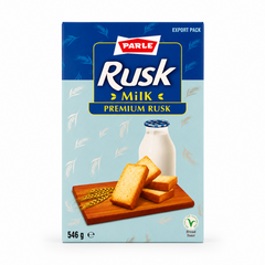 A professional studio product shot of a 546g export cardboard box of Parle Premium Milk Rusk isolated against a pure white background in image_97aa6f.jpg. The packaging features a two-tone blue design with the red and white Parle logo above the prominent product title "Rusk Milk". The lower section displays a wooden cutting board holding crispy golden rusks next to ears of wheat and a fresh bottle of milk. This product is available in the UK at theindianshelf.co.uk.