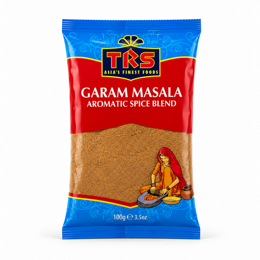 A 100g pouch of TRS Garam Masala centered on a solid white background, featuring a vibrant red and blue packaging design with the TRS logo and a clear window showing finely ground brown spice blend next to an illustration of a traditional Indian woman using a grinding stone. This product is available in the UK at theindianshelf.co.uk.
