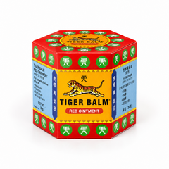 A professional studio shot showcasing the iconic, hexagonal cardboard outer carton for Tiger Balm Red Ointment The box features a striking geometric layout with bright red borders on the top, bottom, and edges, populated with circular green emblems housing white Chinese characters.The main front-facing panel has a warm golden-yellow background, framed by dark blue vertical columns containing gold Chinese script. This product is available in the UK at theindianshelf.co.uk.