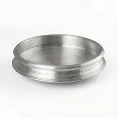 A clean, eye-level studio shot of a traditional Aluminum Uruli (cookware). The vessel is circular with a wide, open top and a shallow depth, featuring a distinctive flared rim with horizontal decorative grooves. It has a brushed metallic finish and is set against a plain, well-lit white background.