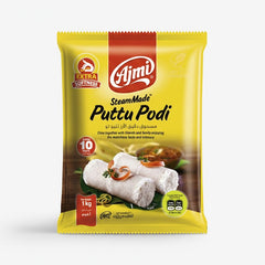This image displays a 1 KG yellow and red package of Ajmi SteamMade™ Puttu Podi, a specially steam-made pure rice flour mix used to prepare Puttu, a traditional Kerala breakfast dish. The product is manufactured by the Ajmi brand. This specific food product is commonly available through various international retailers, including those serving the UK market, such as The Indian Shelf UK.