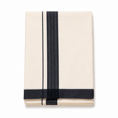 A neatly folded cream men's Kerala mundu (dhoti) centered on a solid white background, featuring a wide vertical textured black woven border (kara), a thin parallel black stripe, and a intersecting black border along the bottom hem fold. Available in the UK at theindianshelf.co.uk.