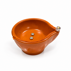 An electric LED pooja diya in a traditional terracotta-brown color with a clear LED bulb at the tip, centered on a solid white background. Available in the UK at theindianshelf.co.uk.