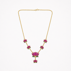 A delicate gold-plated chain necklace featuring multiple magenta-pink enamel lotus motifs arranged along the bottom, centered on a solid white background. Available in the UK at theindianshelf.co.uk.