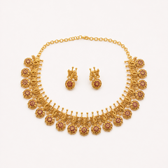 An antique gold-plated heritage jewelry set featuring a traditional peacock choker necklace adorned with ruby red stone circular drops and matching drop earrings, centered on a solid white background. Available in the UK at theindianshelf.co.uk.