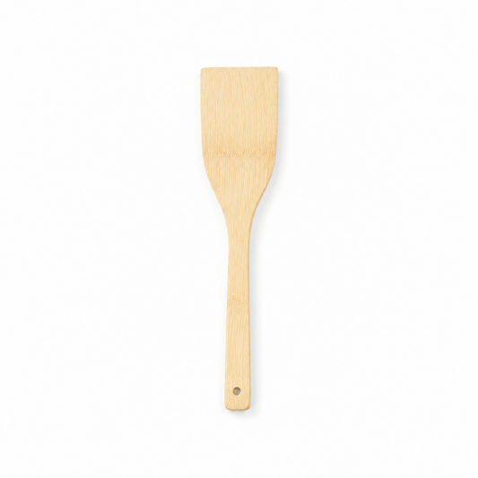 A natural light wood flat cooking spatula turner with a hanging hole at the handle tip, displayed vertically against a solid white background. Available in the UK at indianshelf.co.uk.