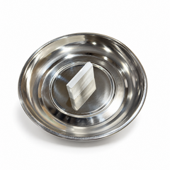 A polished stainless steel coconut breaker featuring a central blade inside a collection basin, centered on a solid white background. Available in the UK at theindianshelf.co.uk.