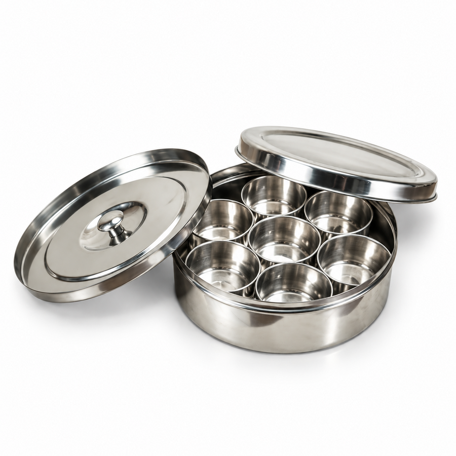 A stainless steel masala box (Anjarai Petti) size 13 a matching spoon, displayed with its lids open on a white background. Available in the UK at theindianshelf.co.uk.