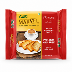 A professional studio shot of a package of Aditi Marvel Premium Milk Rusk. The wrapper features a split design with a bright yellow section on the left and a rich red section on the right. The left side displays the green "Aditi" logo above the bold golden title "MARVEL" and the tagline "HAPPY TREATS FOR HAPPY LIFE." An elegant graphic below shows three crispy, golden-brown rusks arranged on a white plate next to a steaming white cup of milk tea.This product is available in the UK at theindianshelf.co.uk.