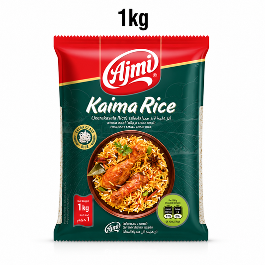 A professional studio product shot of a 1kg pillow pouch of Ajmi Kaima Rice standing vertically against a solid white background, underneath a bold "1kg" text label. The top section of the bag features a red curved panel that houses the white "Ajmi" logo. The main body of the packaging is a deep forest green color, accented with a faint line illustration of rolling hills and agricultural fields. This product is available in the UK at theindianshelf.co.uk.