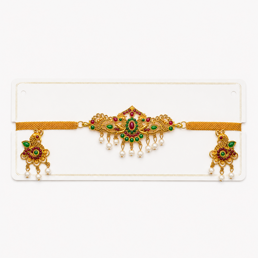 An antique gold-plated temple jewelry mesh choker set displayed on a white card, featuring a peacock centerpiece with red and green kemp stones and dangling pearls with matching earrings, centered on a solid white background. Available in the UK at theindianshelf.co.uk.