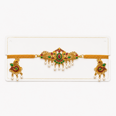 An antique gold-plated temple jewelry mesh choker set displayed on a white card, featuring a peacock centerpiece with red and green kemp stones and dangling pearls with matching earrings, centered on a solid white background. Available in the UK at theindianshelf.co.uk.