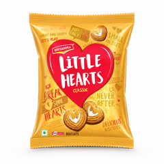 A professional studio product shot of a vertically oriented, metallic gold pillow pouch of Britannia Little Hearts Classic Biscuits isolated against a clean white background. The front design is centered around a large, vibrant red heart graphic containing the bold white text "LITTLE HEARTS" and a smaller yellow "CLASSIC" identifier. The gold background is playfully covered with light red doodle-style text phrases like "BREAK SOME HEARTS", This product is available in the UK at theindianshelf.co.uk.