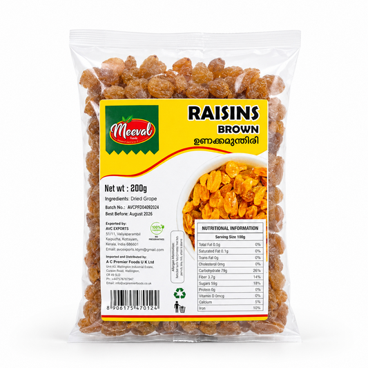 A professional studio product shot of a clear plastic 200g pillow pouch of Meeval Foods Brown Raisins filled with golden-brown dried grapes, standing vertically against a solid white background The front features a prominent yellow and white informational label. The top-left corner of the label displays the red and green "Meeval" logo, while the top-right text reads "RAISINS BROWN" followed by its Malayalam translation. This product is available in the UK at theindianshelf.co.uk.