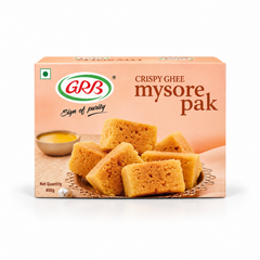 A 400g retail box of GRB Crispy Ghee Mysore Pak featuring brand logos and an arrangement of golden sweet pieces, centered on a solid white background. Available in the UK at theindianshelf.co.uk.