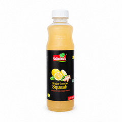 A professional studio product shot of a 700ml bottle of Grandma's Ginger Lemon Squash isolated against a pure white background in image_7afc25.jpg. The transparent bottle reveals a light golden-yellow liquid inside and features a bold black label decorated with graphics of whole and halved fresh lemons, a piece of ginger root, and the red and green brand logo. This product is available in the UK at theindianshelf.co.uk.