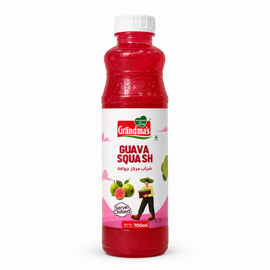A professional studio product shot of a 700ml bottle of Grandma's Guava Squash isolated against a pure white background in image_99de39.jpg. The transparent plastic bottle reveals a vibrant, deep pinkish-red liquid inside and features a white and pink label decorated with illustrations of fresh guavas, a farmer carrying a fruit basket, and the red and green brand logo. This product is available in the UK at theindianshelf.co.uk.