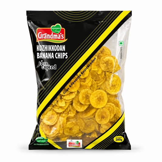 A professional studio shot of the Grandma's Kozhikkodan Banana Chips packaging.The bag features a sleek black design with bold yellow diagonal stripes and the red "Grandma's" logo at the top left. A large transparent window allows a clear view of the thin, golden-yellow round banana chips inside. The text "Kozhikkodan Banana Chips" and "Deep Crunched" are printed prominently.It indicates a net weight of 200g. This product is available in the UK at theindianshelf.co.uk.