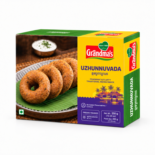 A 350g box of Grandma's Uzhunnuvada featuring golden-fried urad dal fritters on a banana leaf next to a bowl of coconut chutney, centered on a solid white background. Available in the UK at theindianshelf.co.uk.