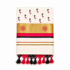 A neatly folded off-white tissue saree centered on a solid white background, featuring fine grid patterns, hand-painted black and red floral motifs, a wide golden kasavu border with two red hand-painted floral emblems, crimson red and black accent stripes, and dual-tone black and red knotted tassels along the bottom fringe.