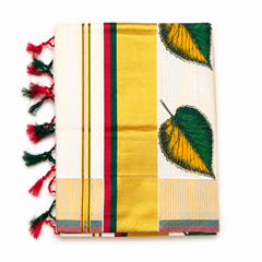A neatly folded off-white tissue saree centered on a solid white background, featuring fine grid check patterns, hand-painted green and yellow leaf motifs, a wide golden kasavu border with red and green accent stripes, and dual-tone red and green knotted fringe tassels along the side edge. Available in the UK at theindianshelf.co.uk.
