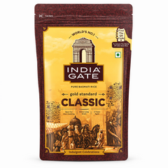 A professional studio shot of an India Gate Classic Basmati Rice resealable pouch. The packaging features a premium gold and deep maroon color palette. The center displays the iconic "India Gate" logo under an illustration of the India Gate monument. Below, "gold standard CLASSIC" is written in bold, elegant typography. The bottom of the bag features a traditional heritage illustration of a royal chariot and figuresThis product is available in the UK at theindianshelf.co.uk.