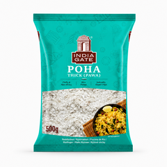 A studio product shot of a turquoise-green pillow pouch bag of India Gate Poha Thick (Pawa) against a solid white background. The top center displays the iconic white-and-brown "INDIA GATE" monument logo, directly above the product title "POHA THICK (PAWA)" in bold white lettering. A large, transparent window across the center clearly showcases the raw white flattened rice flakes inside. In the bottom right corner, This product is available in the UK at theindianshelf.co.uk.
