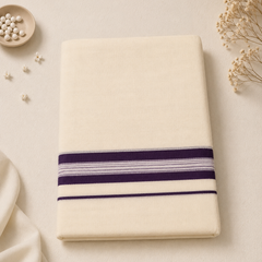 A studio flatlay of a neatly folded cream Kerala Double Mundu on a light textured background. The cotton textile features a distinct horizontal border with deep purple bands and fine lavender pinstripes. A small dish of white beads and dried flowers decorate the corners. Available in the UK at theindianshelf.co.uk.