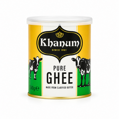 A 200g tin can of Khanum Pure Ghee centered on a solid white background, featuring a yellow, white, and green label design with a black Khanum emblem and illustrations of two dairy cows. This product is available in the UK at theindianshelf.co.uk.
