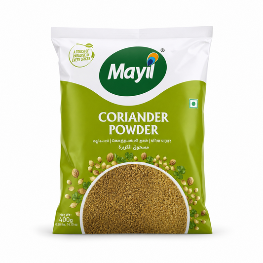 A professional studio shot of the Mayil Coriander Powder packaging. The bag features a clean white top section with a green "Mayil" logo and a small leaf icon with the text "A TOUCH OF PARADISE IN EVERY SPICESThis product is available in the UK at theindianshelf.co.uk.