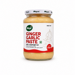.A transparent 400gm glass jar filled with smooth, golden-beige Mayil Ginger Garlic Paste, featuring a clean white front label with red text and illustrations of ginger and garlic roots, centered perfectly against a solid white background. Available in the UK at theindianshe