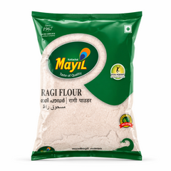 A high-quality studio shot of a packet of  Mayil Ragi Flour. The packaging features a vibrant dark green design with a large green oval containing the "Mayil" peacock logo and the slogan "Taste of Quality". The words "RAGI FLOUR" are prominently displayed in bold black text, with the name also provided in Malayalam, Hindi, and Arabic. The packet includes several quality seals, such as "Natural Ingredients Premium Quality" and "100% Natural"This product is available in the UK at theindianshelf.co.uk.
