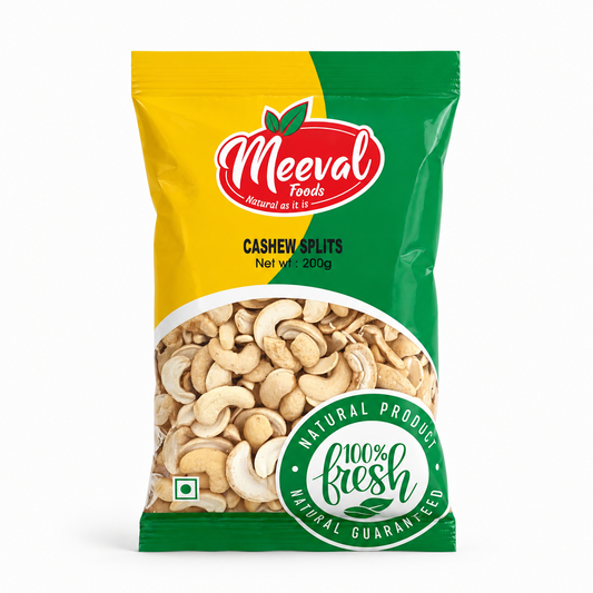 A professional studio shot of the Meeval Cashew Splits packaging The bag features a vibrant, split-color design with yellow on the left and dark green on the right. The red and white oval "Meeval Foods" logo is centered near the top with the tagline "Natural as it is." A large semi-circular transparent window in the lower half showcases the high-quality, pale cream-colored split cashews inside.This product is available in the UK at theindianshelf.co.uk.